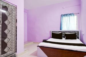 SPOT ON Hotel Sunshine Lodging في Āsansol: غرفة نوم مع سرير وبجدران أرجوانية ونافذة