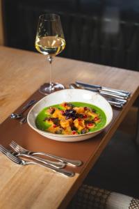 a plate of food on a table with a glass of wine at Alpinhotel Berghaus spa in Tux