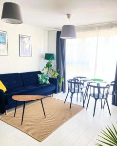 ein Wohnzimmer mit einem blauen Sofa und einem Tisch in der Unterkunft Apartament MONSTERA in Dziwnówek