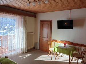 a living room with a table and a television on the wall at Ferienhaus Alpenblick in Heiligenblut