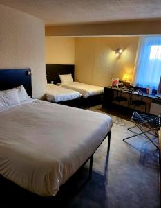 een hotelkamer met 2 bedden en een bureau bij The Originals City, Hôtel Le Forum, Strasbourg Nord in Schiltigheim