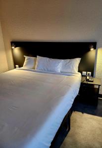 a large white bed in a hotel room at The Originals City, Hôtel Le Forum, Strasbourg Nord in Schiltigheim