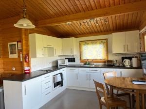 a kitchen with white cabinets and a wooden ceiling at Holme Woodmans Lodge in Holme