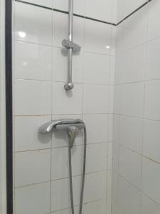 eine Dusche mit einem Schlauch in einem weiß gefliesten Bad in der Unterkunft L'appartement florentin in Saint-Germain-en-Laye