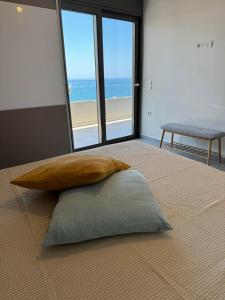 a pillow on a bed with a view of the beach at zonapartments A sea view-city center in Chania