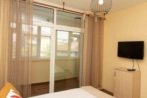 een slaapkamer met een bed, een tv en een raam bij Momento Apartment in Kyustendil
