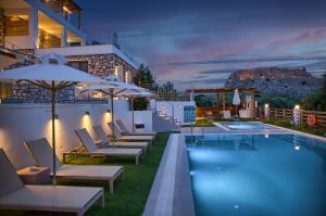 哈拉奇KOUROS STONE SUITES的建筑物旁边有带椅子和遮阳伞的游泳池