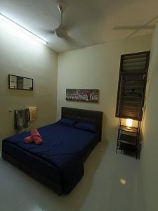 a bedroom with a blue bed and a lamp at Healing Homestay in Kangar
