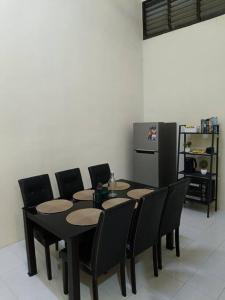 a dining room with a table and chairs and a refrigerator at Healing Homestay in Kangar
