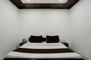 een slaapkamer met een wit bed met zwarte kussens bij OYO Flagship SAADAR HOTEL AND BANQUET in Kānpur