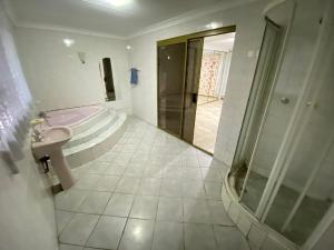 MOMENTS Of JOY GUESTHOUSE AND SPA AT CARNIVAL في Brakpan: حمام مع دش ومغسلة وحوض استحمام
