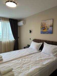 a bedroom with a large white bed with a window at Hotel Trend in Ravda