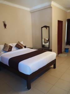 una camera con un grande letto e uno specchio di Munnar Mount Shelt Hotel a Munnar