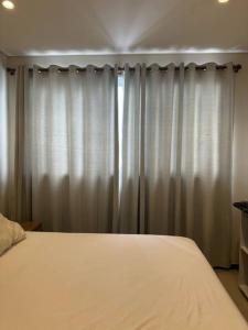 1 dormitorio con cama blanca y cortinas en Apto Lujoso, piscina climatizada, jacuzzi, gym. en Asunción