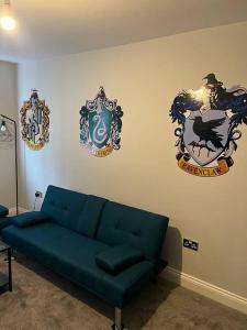 a living room with a blue couch and some decorations on the wall at Potters Escape- Warner Bros Studios & London in Leavesden Green