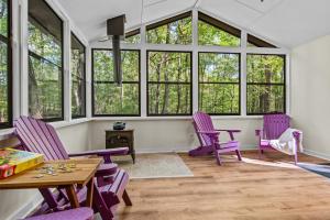 a room with purple chairs and tables and windows at Beaverdam Bliss Cabin on 14 acres in Madison
