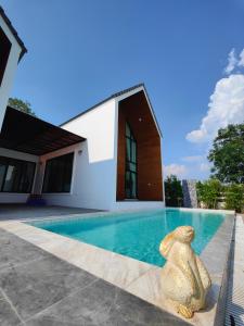 une statue d'un ours assis à côté d'une piscine dans l'établissement ASTRID PoolVilla KhaoYai, à Pak Chong