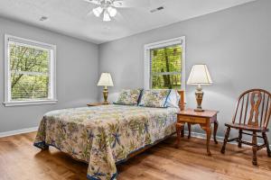 a bedroom with a bed and a chair and two windows at Beaverdam Bliss Cabin on 14 acres in Madison