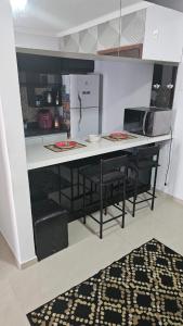 a kitchen with a counter with chairs and a refrigerator at Apartamento Flat Palladium completo e mobiliado in São Vicente