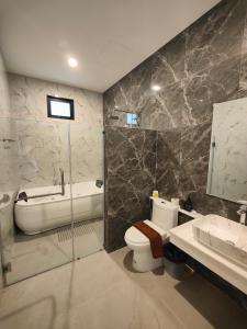 La salle de bains est pourvue de toilettes, d'un lavabo et d'une baignoire. dans l'établissement ASTRID PoolVilla KhaoYai, à Pak Chong
