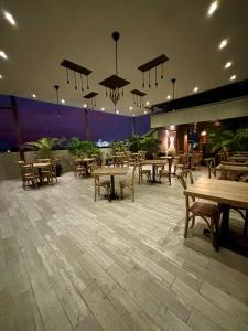 un ristorante con tavoli e panche in legno e luci di Hotel San Miguel Imperial a Santa Marta