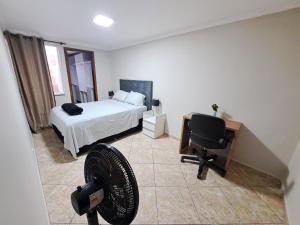 a bedroom with a bed and a desk and a chair at Casa Grande Familia in Brasilia