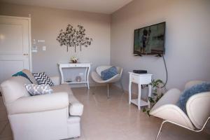 ein Wohnzimmer mit weißen Möbeln und einem TV in der Unterkunft Hermoso Departamento equipado en Mendoza in Barraquero