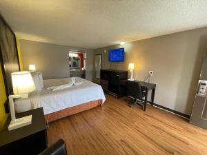 a hotel room with a bed and a desk and a television at Super 8 by Wyndham Monroe in Monroe