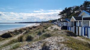 a row of houses on a beach next to the ocean at Beach-near cozy cottage in Höllviken