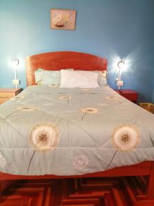 a bedroom with a large bed with white sheets and two lamps at Naty's Guest House in Cusco
