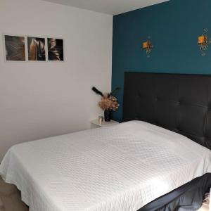 a bedroom with a white bed with a black headboard at L'Air de Caen in Esquay-Notre-Dame