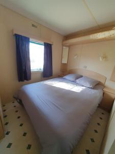 1 dormitorio con 1 cama blanca grande y ventana en Camping du Lac MH Azur, en Égletons