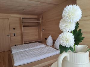Cette petite chambre comprend un lit avec un vase de fleurs. dans l'établissement NEU Uuszit985 - auszeit mit ausblick, à Schwarzenberg im Bregenzerwald