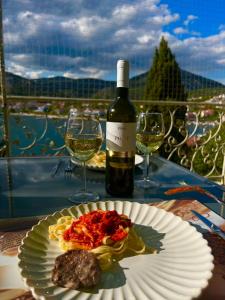 butelkę wina oraz talerz jedzenia i kieliszki do wina w obiekcie Apartament Abi w mieście Vranjica