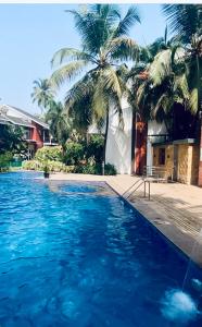 a swimming pool with blue water and palm trees at Luxury apartment Blue lagoon in Goa