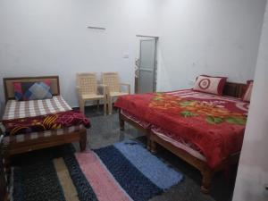 1 dormitorio con 2 camas, silla y mesa en happy khajuraho home stay, en Khajurāho