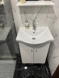 a white sink in a bathroom with black tiles at Apartman Repac in Ostrovo