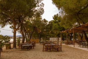 a group of tables and chairs on a beach with trees at Ergon Beach House Nikiti in Nikiti