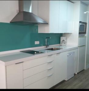 cocina con armarios blancos, fregadero y fogones en Apartamento Playa Algaida, en Sitio de Calahonda