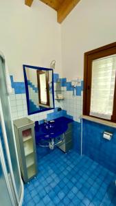 a blue tiled bathroom with a sink and a mirror at ENJOY HOUSE in Ronchi