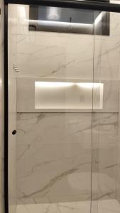a glass door in a room with white marble at Apartamento Terracota in Piumhi