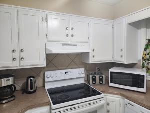 a kitchen with white cabinets and a stove and a microwave at Cozy bungalow in Calgary