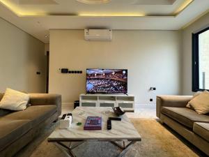 a living room with a couch and a flat screen tv at شقة فاخرة ٣ غرف وصالة دخول ذاتي ٩ in Riyadh