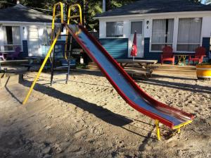 a slide on a playground in front of a house at Wu Wu's Cabins in Wasaga Beach