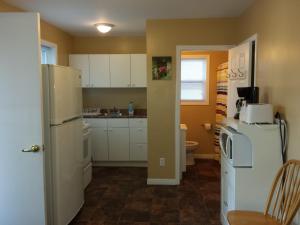 a kitchen with white cabinets and a refrigerator at Wu Wu's Cabins in Wasaga Beach