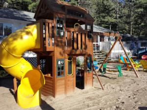 a playground with a play house and a slide at Wu Wu's Cabins in Wasaga Beach
