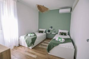 2 Betten in einem Zimmer mit grünen Wänden in der Unterkunft Ad un passo dal molo in Porto Torres