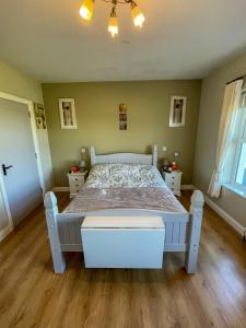Cama blanca en habitación con suelo de madera en Valley View 1 (Tourist board registered), en Tamnyrankin