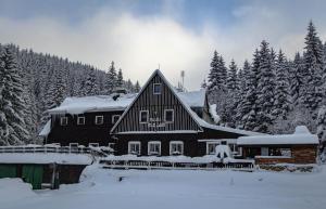 a house covered in snow in front of trees at Bouda Bílé Labe in Špindlerův Mlýn