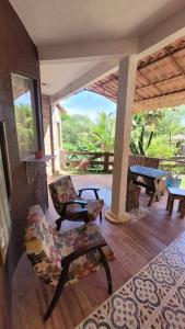 um alpendre com uma cadeira, uma mesa e um banco em Villa Blue Point - Chácara com piscina e 4 quartos em Vila Velha